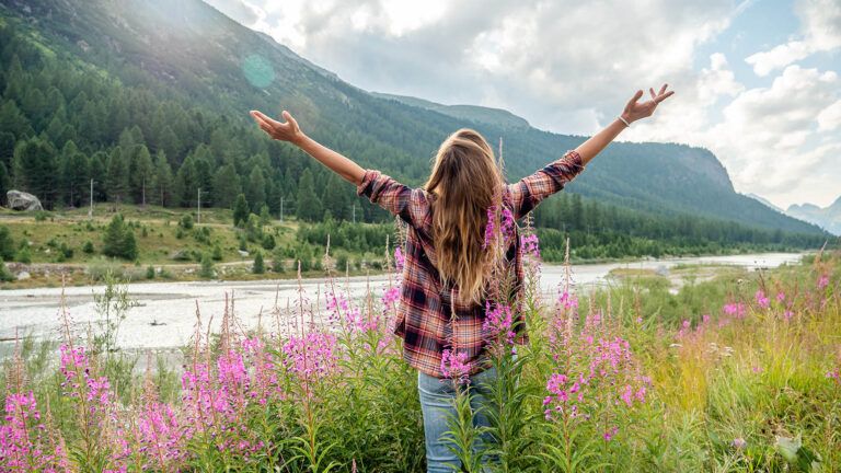Woman with her arms raised in a field after reading Easter quotes