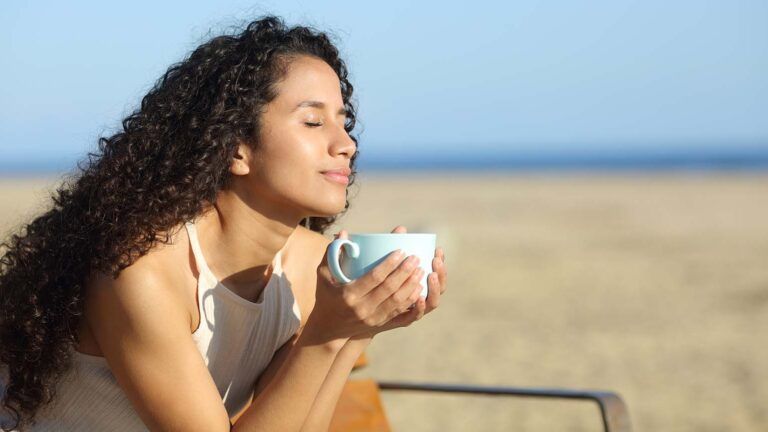 Woman with her eyes closed saying her spring prayers while she drinks coffee