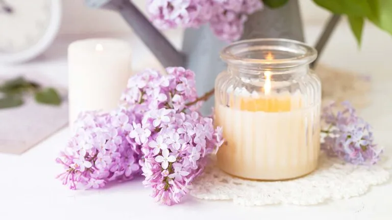 a candle for saying spring prayers surrounded by lilac flowers