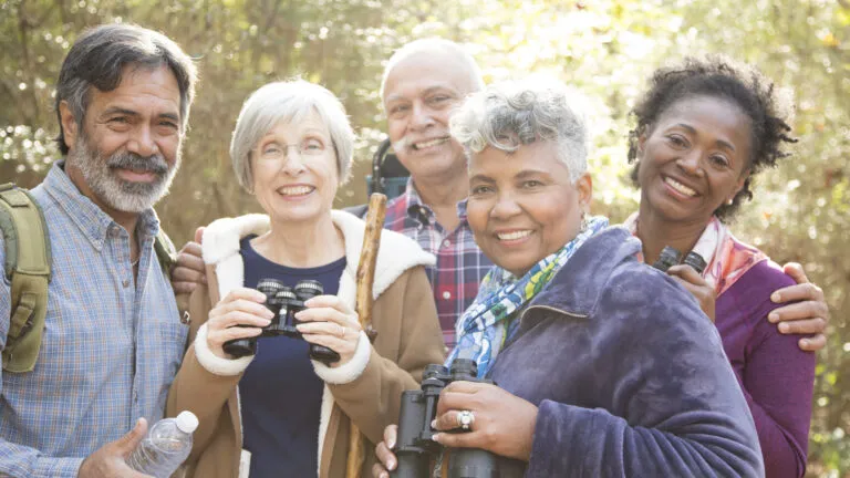 A group of diverse senior friends hiking in the woods.