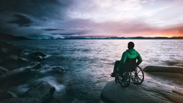 A man in a wheelchair looks out at the ocean