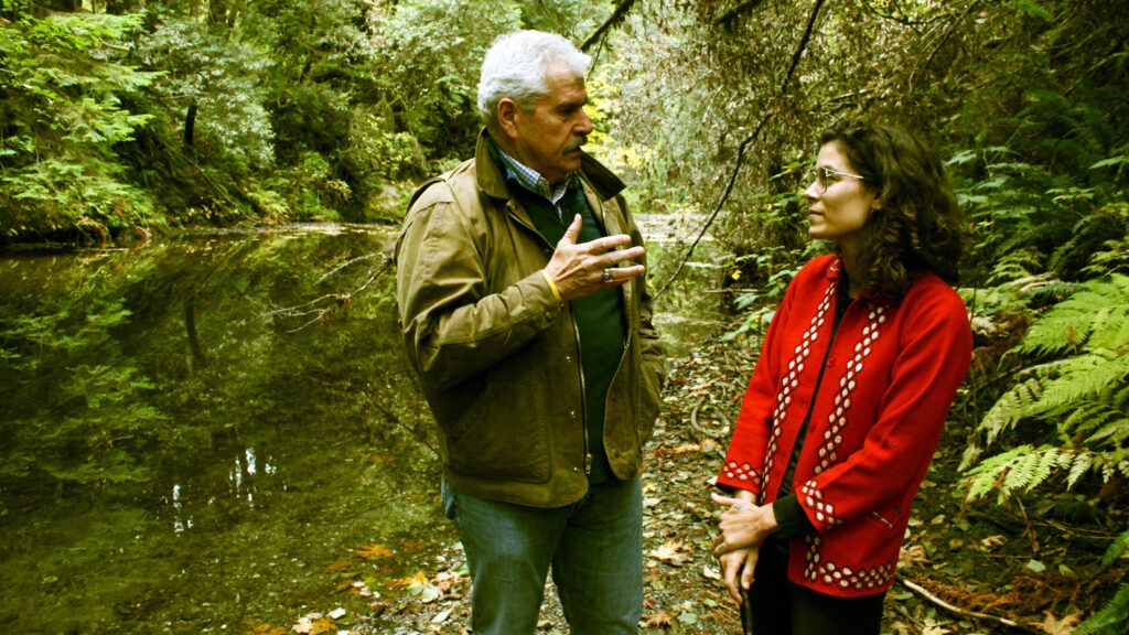 Jacqueline Suskin having a conversation with Neal in the forest.