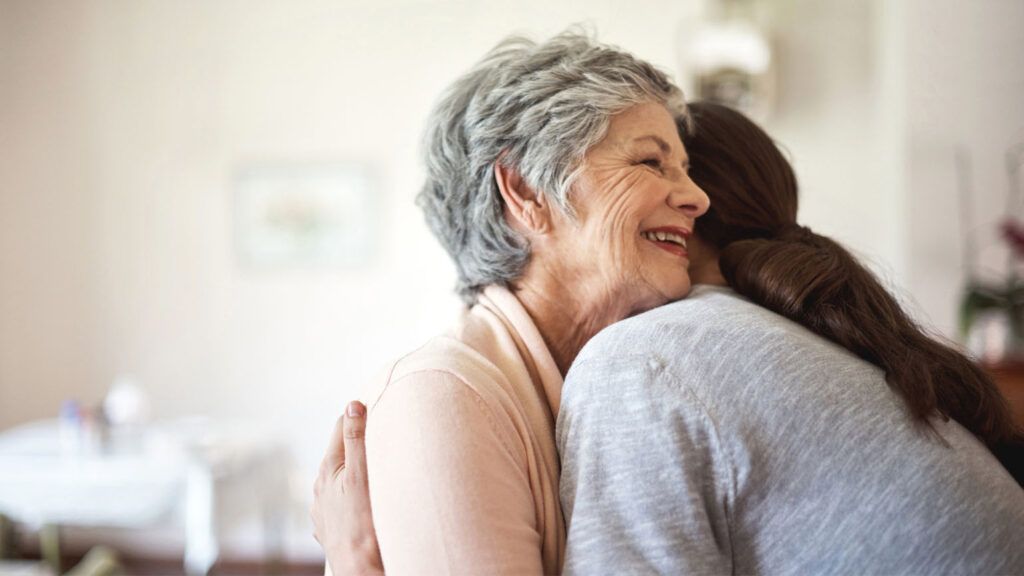 A caregiver daughter hugging her elderly mother.
