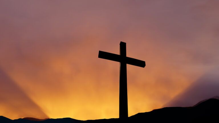 The empty cross stands tall in the face of the sunrise