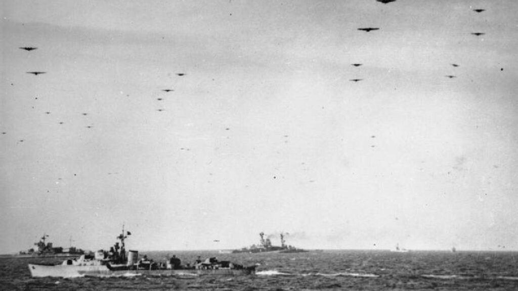 The Royal Navy during the Second World War- Operation Overlord (the Normandy Landings)- D-day 6 June 1944 Glider borne troops passing over units of the Royal Navy on their way to the invasion beaches of Normandy. In the background are the battleships HMS