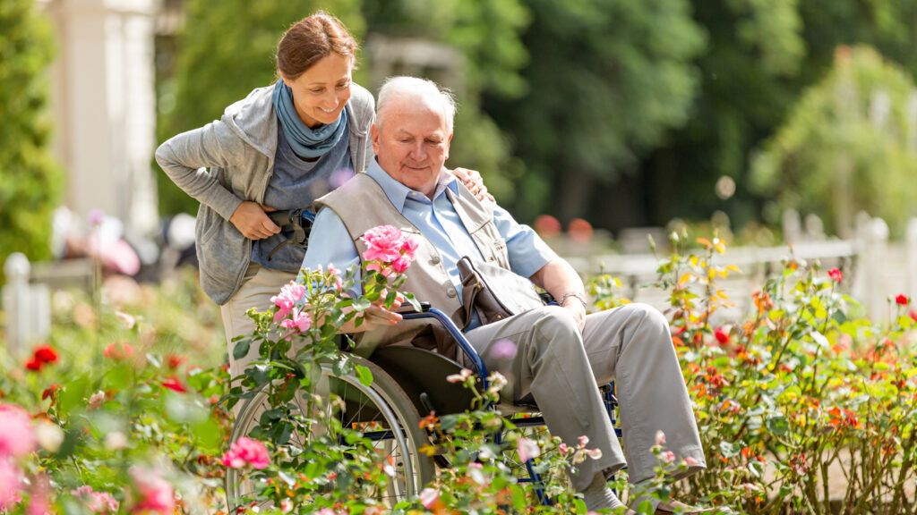 A woman taking her elderly father around the garden.