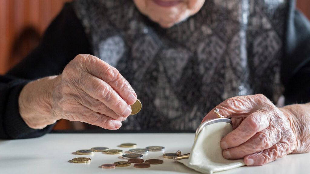 An elderly woman counting her change from her coin purse.