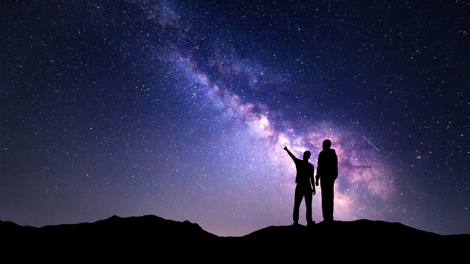 Two silhouettes of people stargazing.