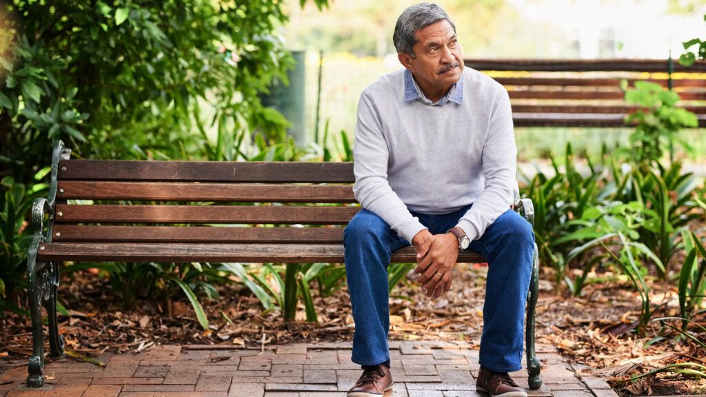 A man sitting on a park bench alone.
