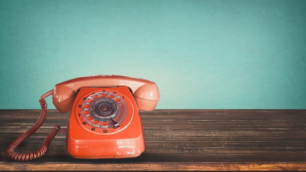 A vintage orange rotary phone.