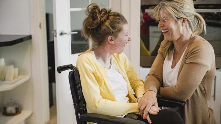 A caregiver parent laughing with her special needs daughter.