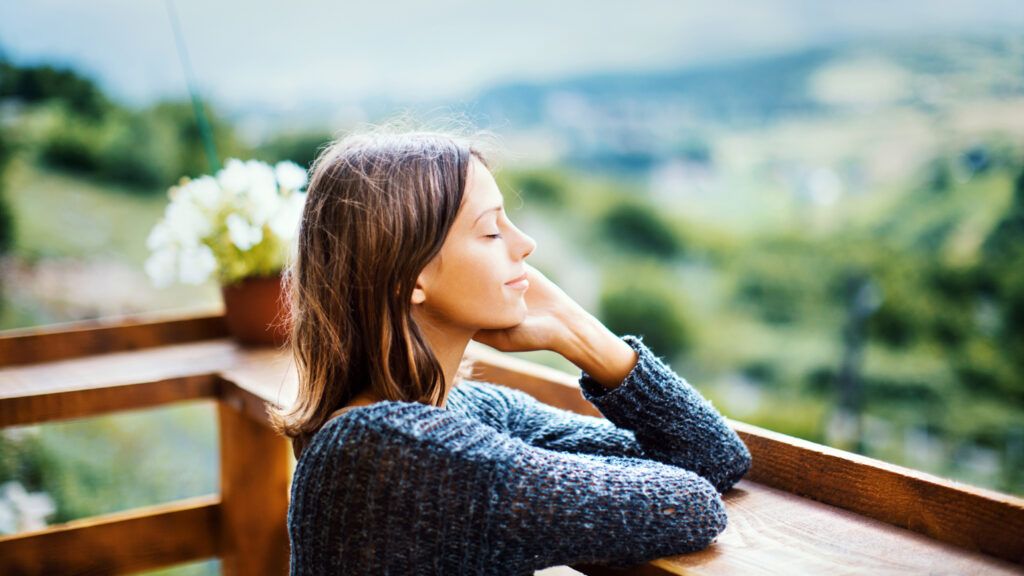 A woman with a calm mindset and closed eyes enjoying the outdoors.