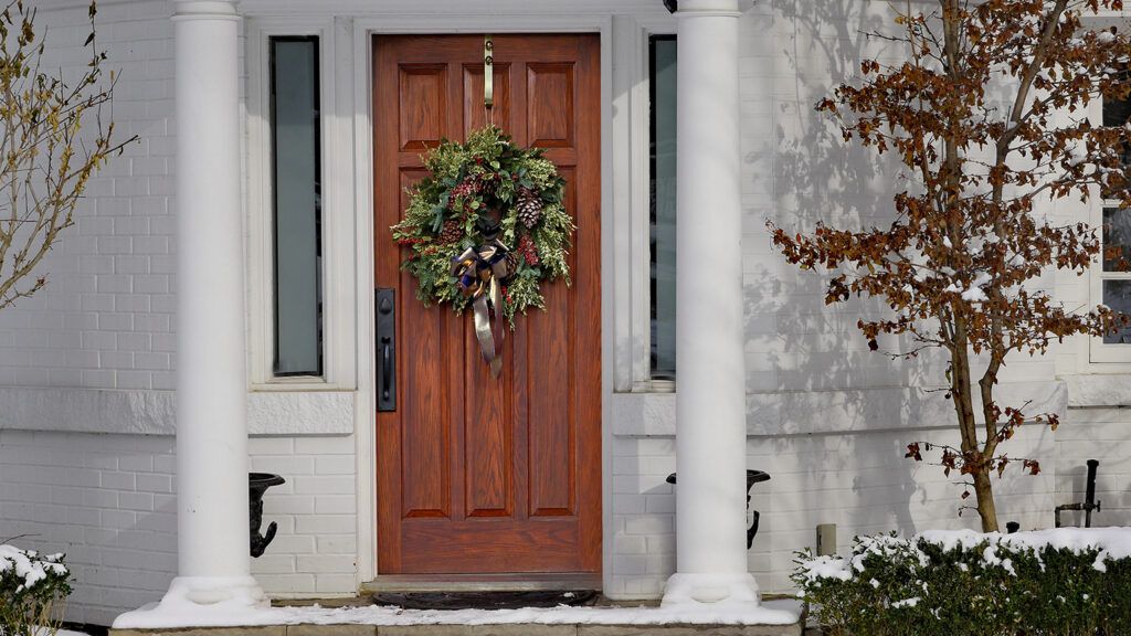A Christmas wreath on the door of a white house