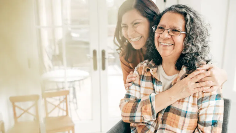 A adult daughter with her aging mother in a happy, loving embrace.