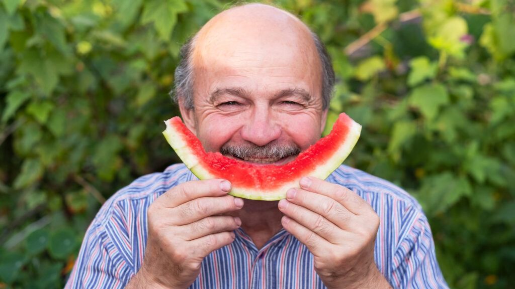 An older gentleman enjoying a slice of watermelon.