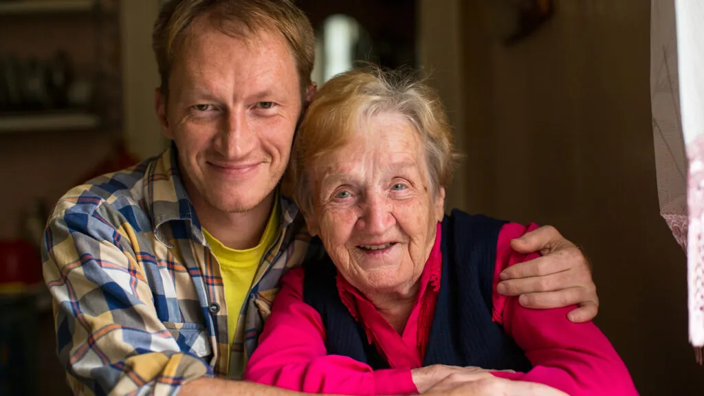 Portrait of old woman with his adult grandson.