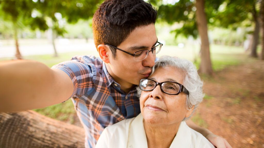 A millennial grandson showing affection to his grandmother.