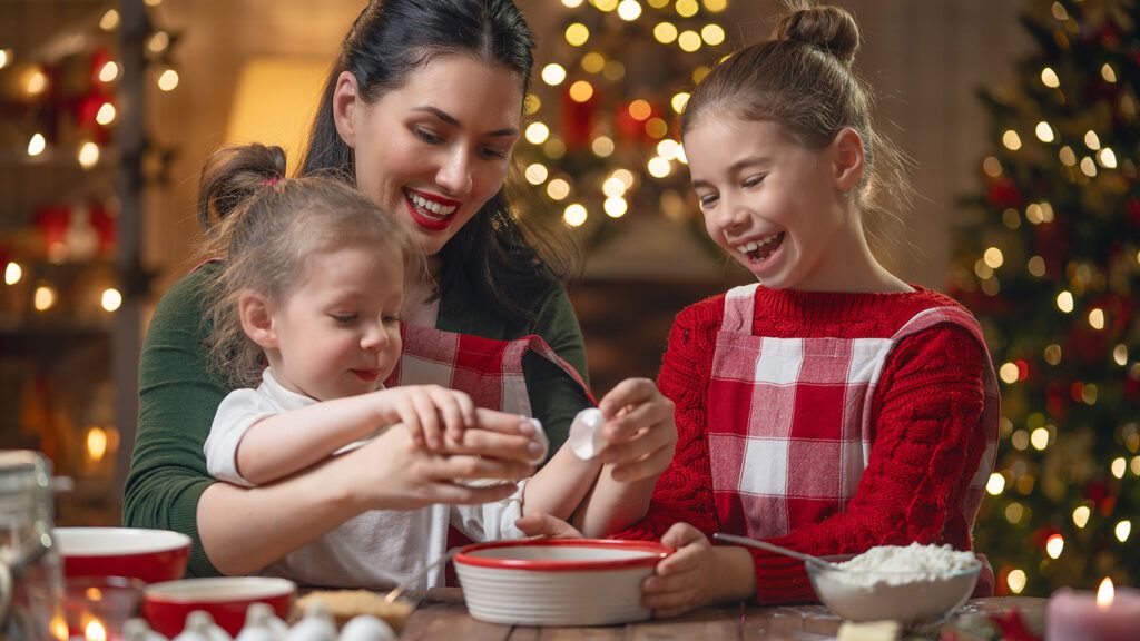 A mother does some Christmas baking with her two young daughters
