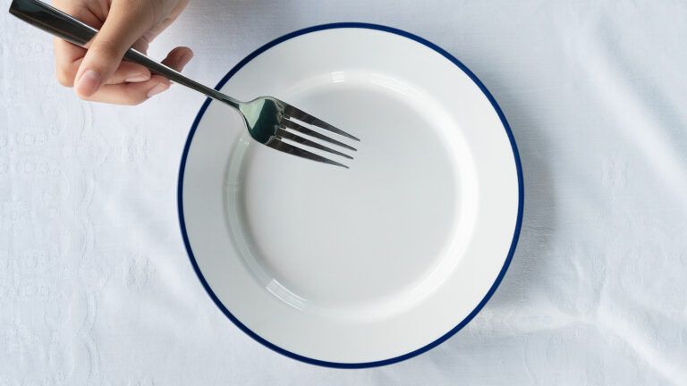 The hand of a woman diner clasps a fork