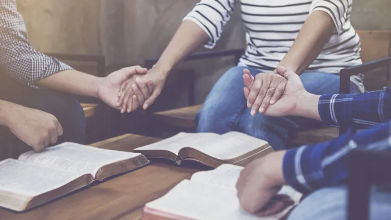 A group holding hands in prayer.