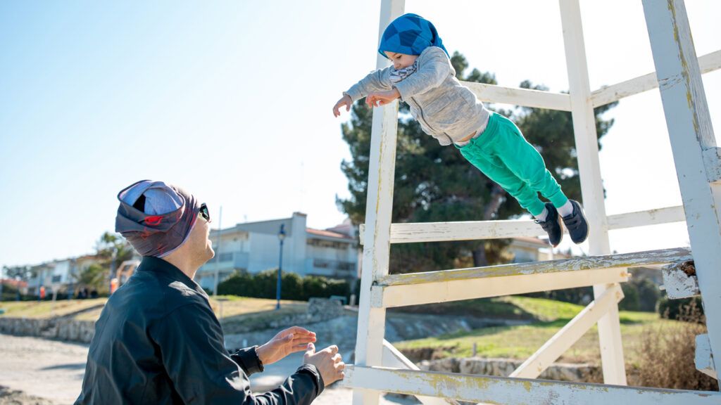 A child and parent performing a trust fall.