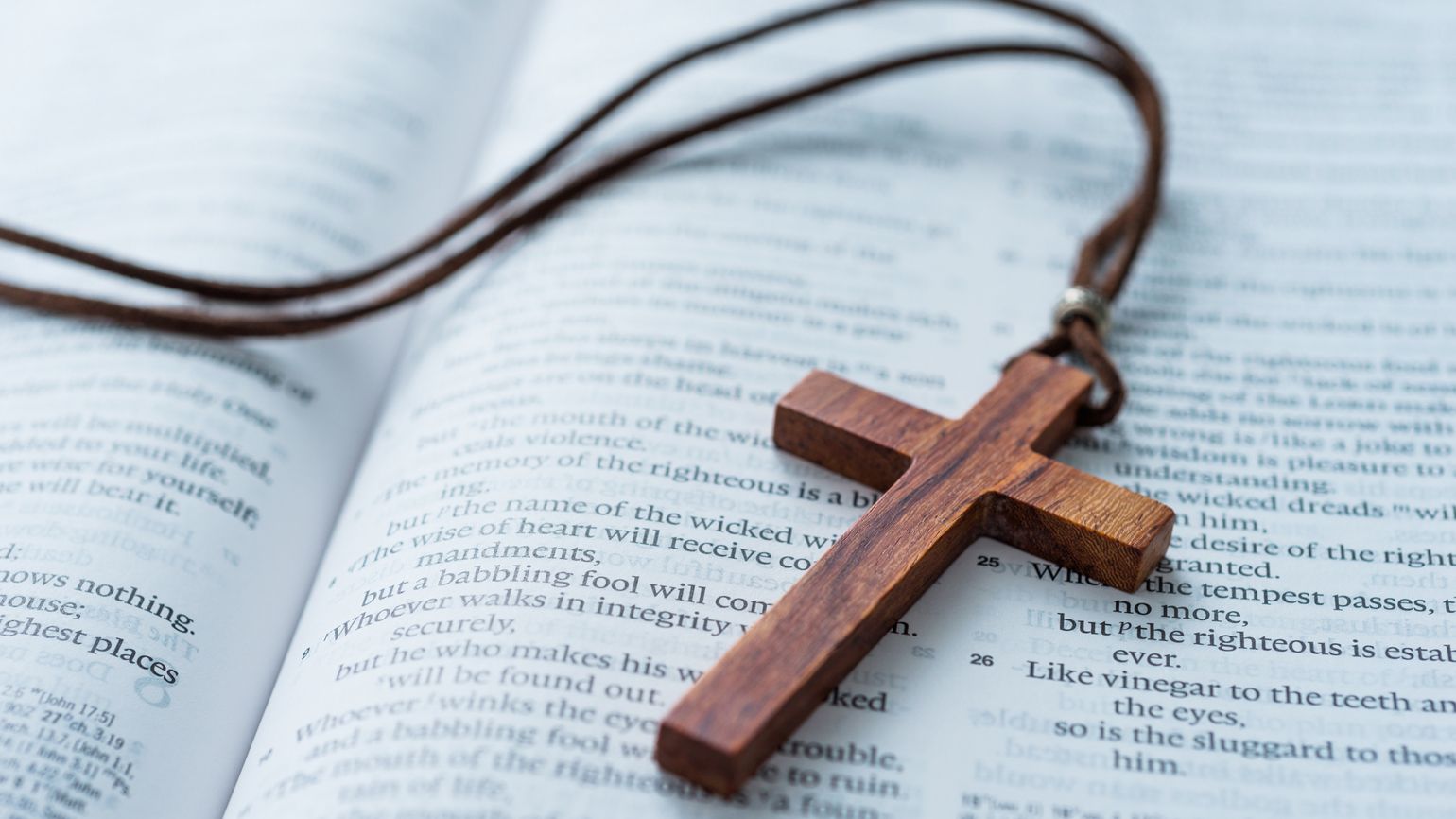 A necklace with a prayer cross resting on a Bible.