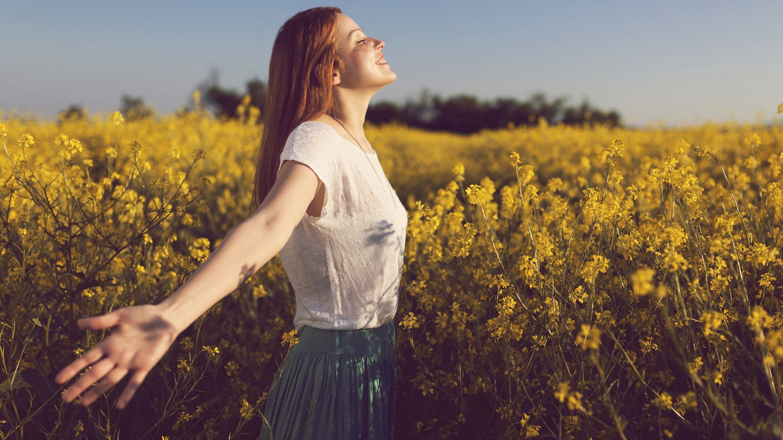 A woman with her arms outstretched in a flower field.