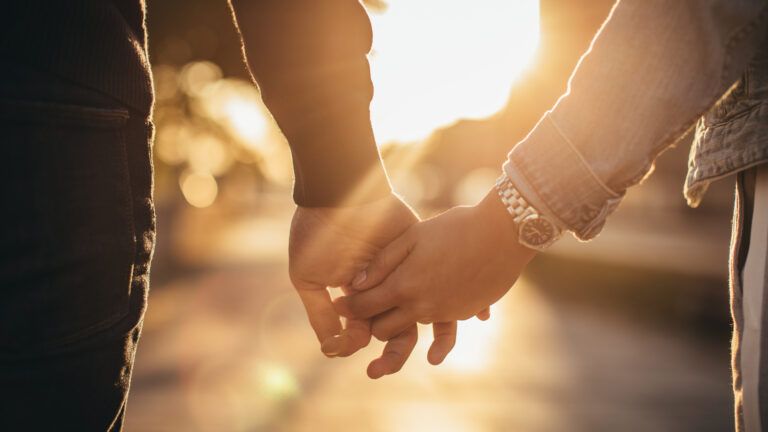 Couple holding hands at sunset to celebrate their love on valentine's day