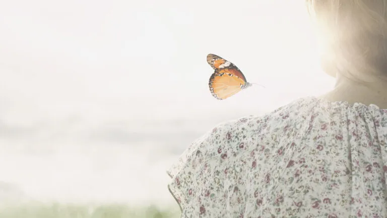 A butterfly hovering over a girl's shoulder.