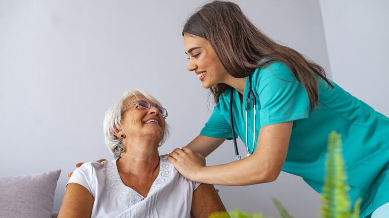 A home care aide helps a patient.