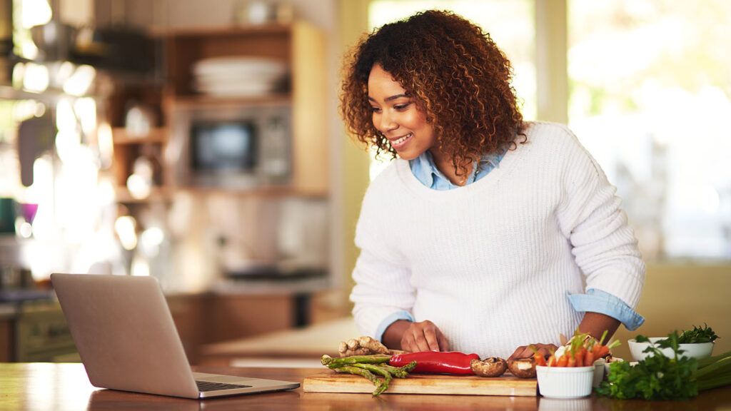 Woman using a laptop while cooking