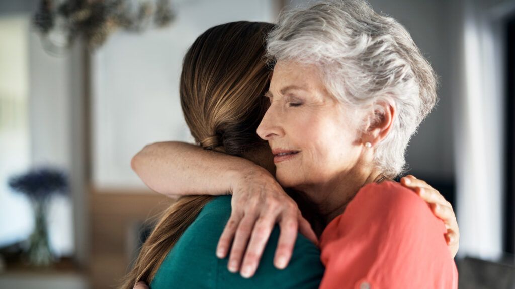 A caregiver hugs an aging loved one.