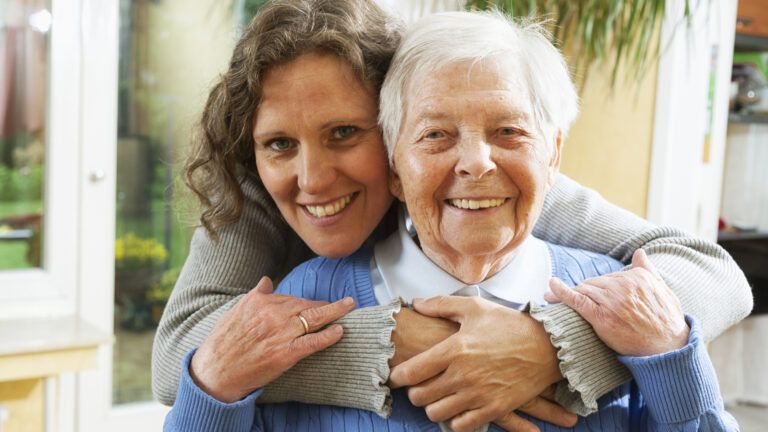 A woman and her aging mother in a loving embrace.