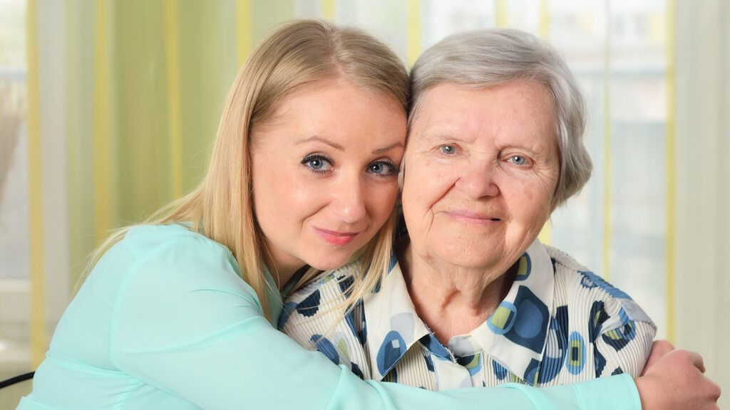An adult daughter embraces her senior mother