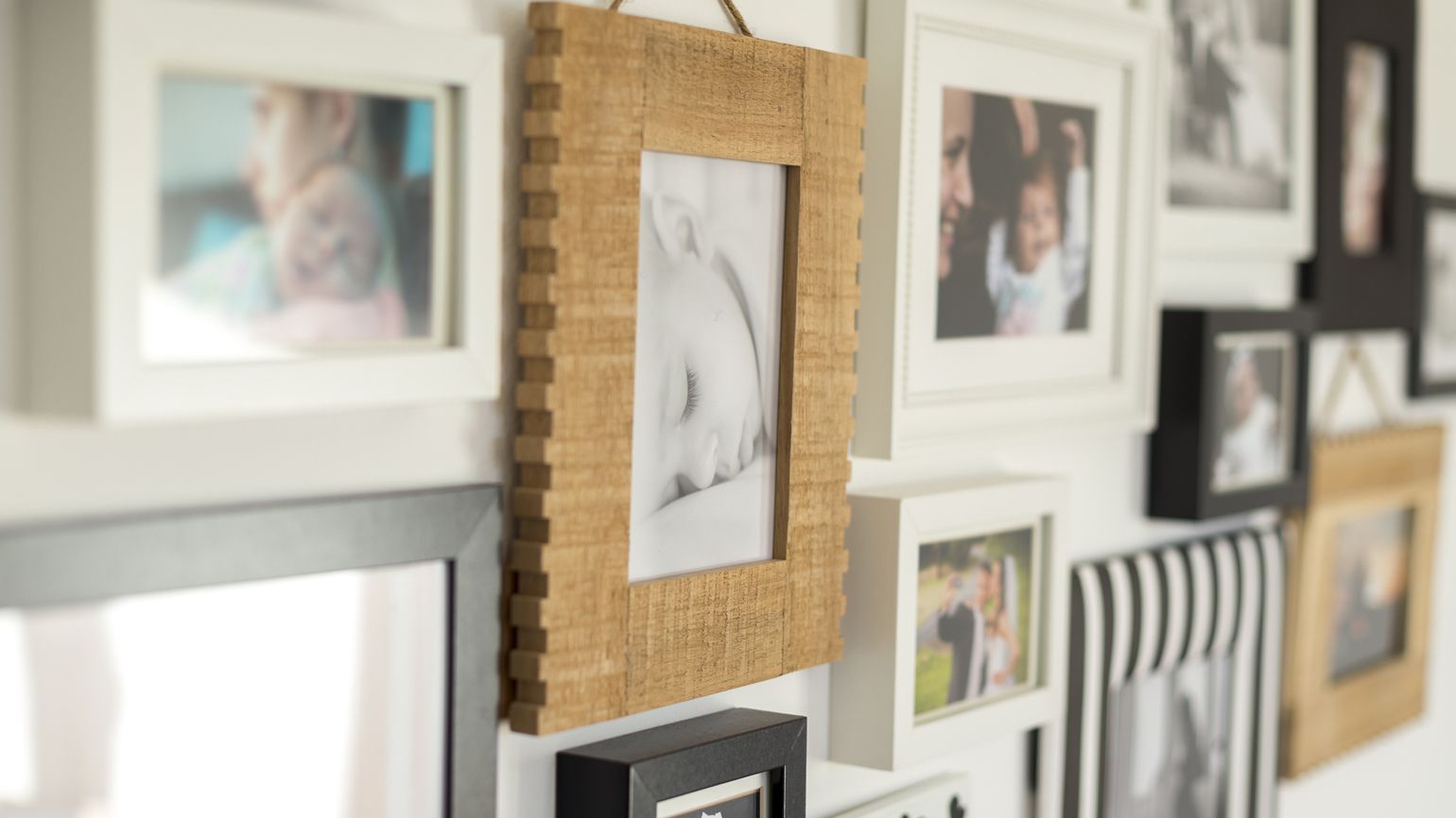 A white wall with photos of the family in various photo frames.
