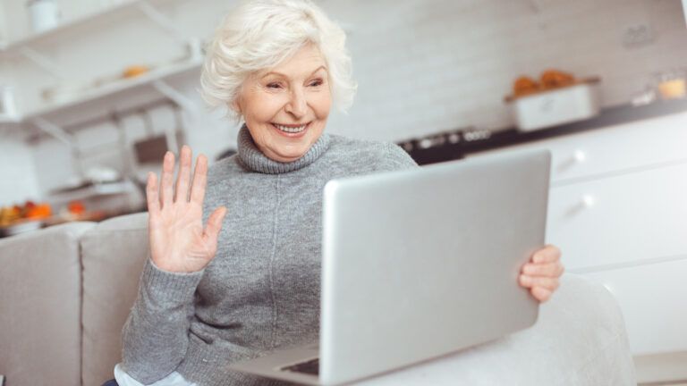 A woman in her golden years using a laptop to video chat.