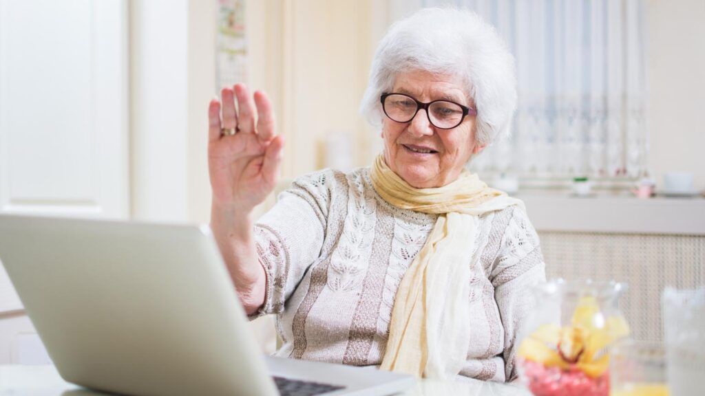 An elderly woman uses her laptip to video chat relatives.