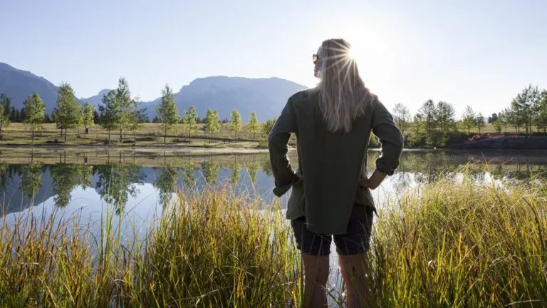 Woman with hands on hips at a mountain lake.