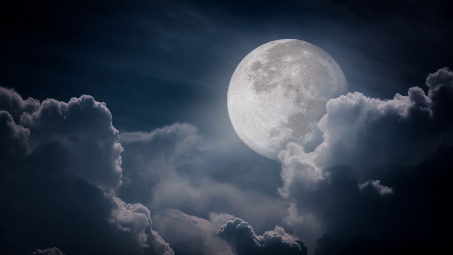 A full moon at night with clouds surrounding.