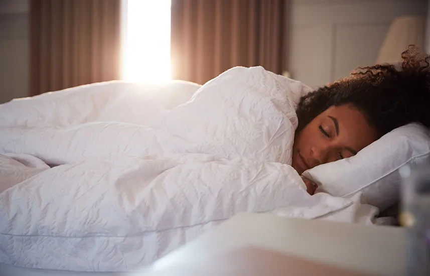 Woman sleeping as day breaks through curtains