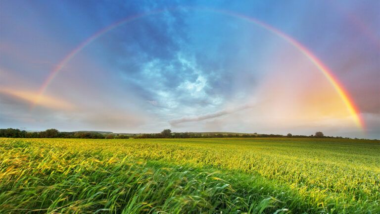 A rainbow arcs over a lush green valley