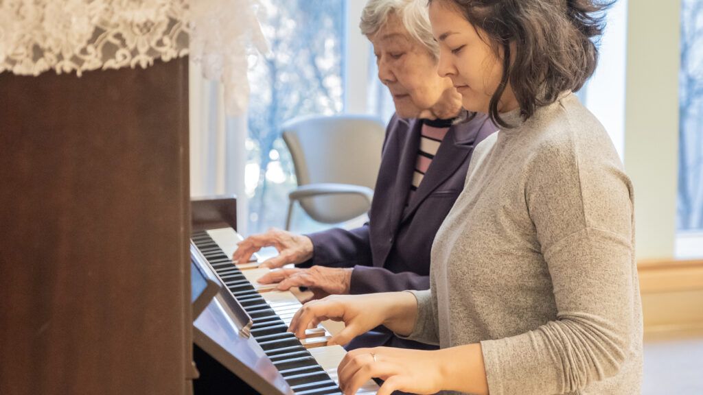 A caregiver plays piano with her client.