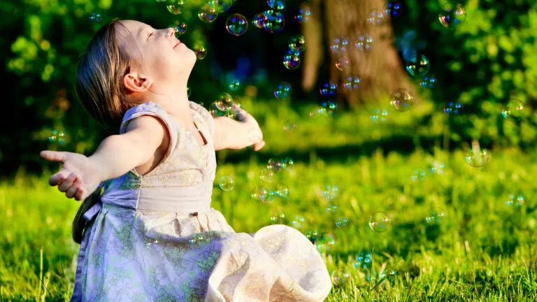 A young girl enjoys blowing bubbles