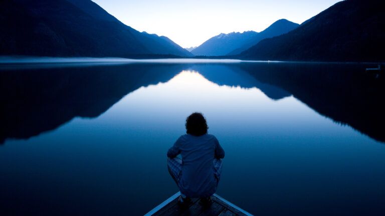 Man on a lake facing the mountain