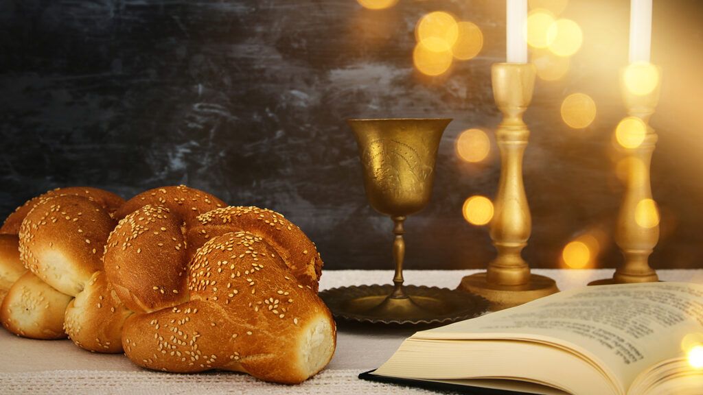 Challah bread, wine and candles are placed on a table for Shabbat