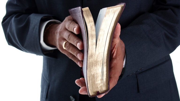 A Bible rests in a pastor's hands