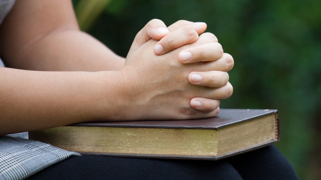 A woman's hands clasped in prayer