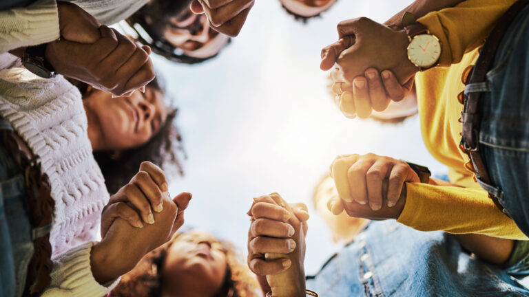 A group of people holding hands ready to change their lives spiritually in 2023