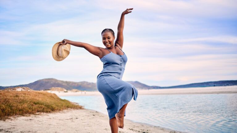 Woman dancing on the beach excited to change her life spiritually in 2023