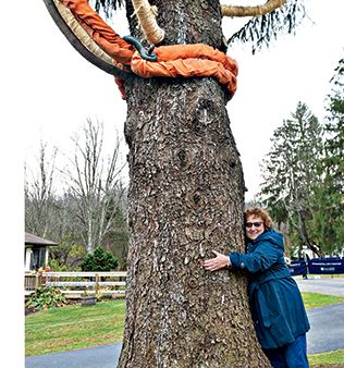 Carol Schultz hugs her Norway spruce prior to its trip to NYC